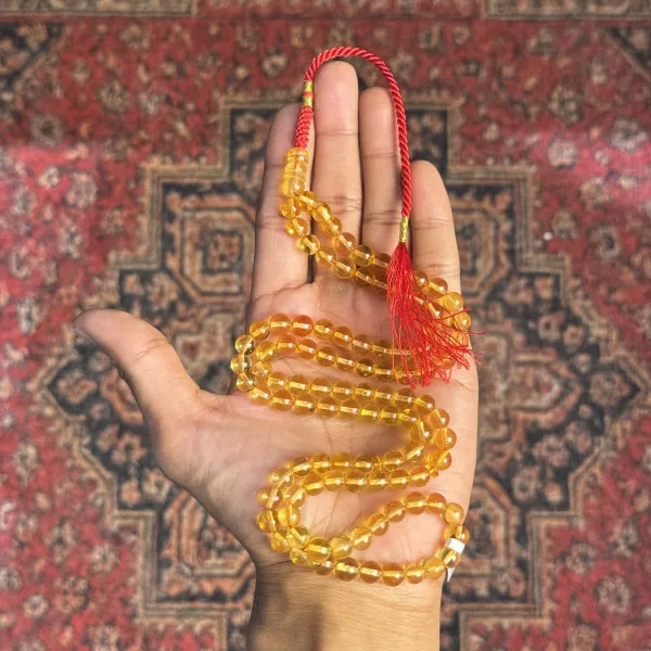 مسباح كهرمان طبيعي – عسلي شفاف، شرابة حمراء، حبات بيضاوية
